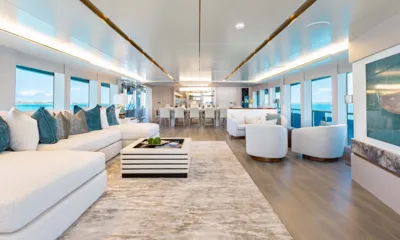 Amore: Salão longo e iluminado com sofá modular branco, poltronas e uma mesa de jantar ao fundo