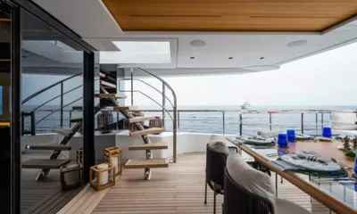 Halara: Mesa de jantar externa posta sobre um deck de teca ao lado de uma escada em espiral com vista para o mar