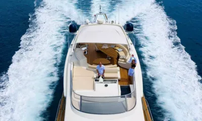888: Flybridge con timone, sedute curve e tavoli sotto un tendalino, con la scia alle spalle