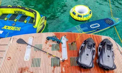 FG Star mini: Piattaforma di poppa in teak con scooter subacquei, pagaia e tavola da SUP accanto a gonfiabili trainabili in acqua verde
