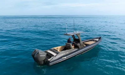 Mave: Bote auxiliar inflável rígido escuro com dois motores de popa e condutor em mar azul aberto