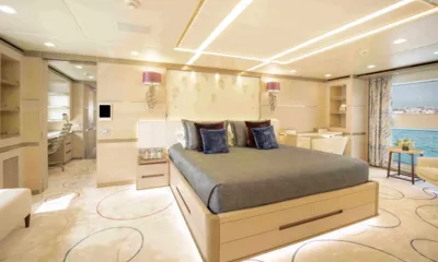 Charade: Cabine dupla grande com roupa de cama cinza, área de escrivaninha e janela ampla para o mar