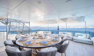 Charade: Mesa redonda posta para o jantar em um convés de popa sombreado com sofás e vista para o mar