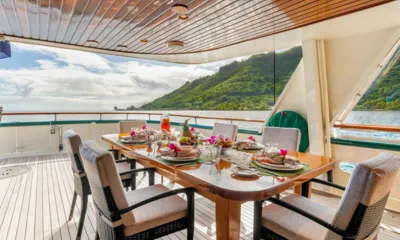 Askari: Set dining table for eight on a shaded aft deck facing green hills