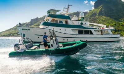 Askari: Green inflatable tender speeding past the anchored yacht near green mountains