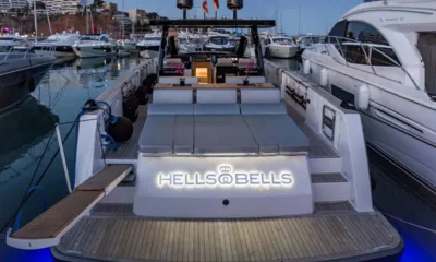 Hells Bells: 夕暮れのマリーナの船尾、照明付きの船名パネル、後部のサンパッド、チークのスイムプラットフォーム、パッセレール