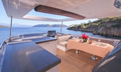 La Luna: Mesa de jantar sombreada do flybridge posta com flores, com o leme e colinas costeiras ao fundo
