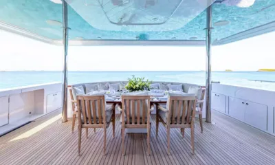 No Shortcuts: Covered outdoor dining table with teak chairs and curved banquette overlooking the sea