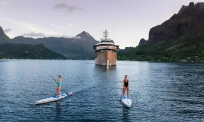 La Datcha: Deux femmes sur des paddles, avec le yacht à l'ancre dans une baie de montagne