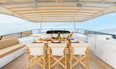 Elegant: Mesa de jantar sombreada no deck com frutas e taças, cadeiras de diretor voltadas para o leme