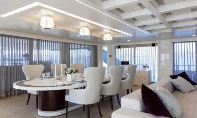 Quinta Essentia: Mesa de jantar oval com cadeiras brancas, luminárias de teto e cortinas leves ao lado de um sofá