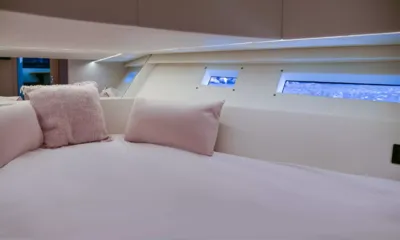 Big Baloon: Cama con cojines rosas bajo estrechas ventanas del casco y suave iluminación lineal