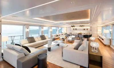 M55: Salone principale luminoso con divani chiari, tappeto e zona pranzo accanto a grandi finestre