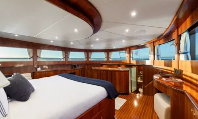 WW: Cabine com cama grande, marcenaria de madeira e uma ampla faixa de janelas voltadas para o mar