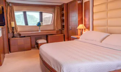 Camy Ed: Cabine com cama de casal, cabeceira estofada, móveis de madeira e uma janela com flores