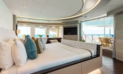 Odyssea: Cabine principal com cama grande, escrivaninha, tela de parede e portas de vidro que abrem para um deck
