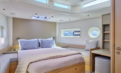 N ICE: Cabine com cama de casal, almofadas azuis, vigia, banco lateral e pequena escrivaninha