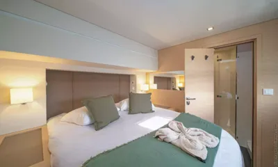 Okinawa: Double cabin with green throw and cushions, bathrobe on bed and ensuite door open