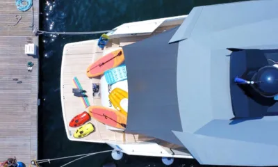 Pangea II: Vista dall'alto della poppa allestita con tavole da SUP, scooter subacquei e tappetini galleggianti accanto a un molo
