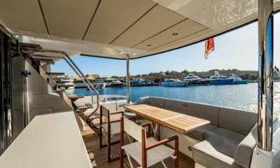 Aquanaut: Deck de popa sombreado com mesa de teca, cadeiras e banco corrido com vista para um porto