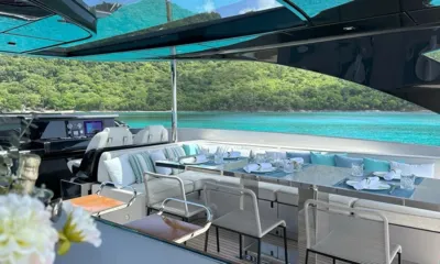 Noi: 緑の湾を望む、操舵席の横にある日よけ付きフライブリッジのセッティング済みダイニングテーブル