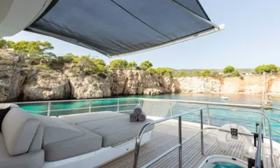 Mio Barco: Colchonete de sol no deck superior sob um toldo com hidromassagem, com vista para uma enseada turquesa e penhascos