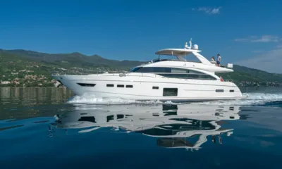 Larimar II: Yacht a motore in navigazione su acqua calma che riflette lo scafo, colline verdi sullo sfondo