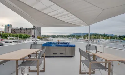 Ascente: Deck superior sombreado com hidromassagem e mesas com cadeiras com vista para uma marina