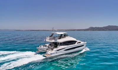 Explorion: Catamarã em movimento no mar azul visto de cima, com um pequeno barco levado na popa