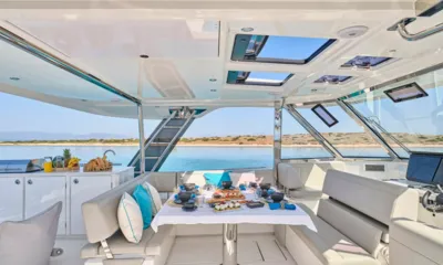 Explorion: Mesa posta com comida no convés superior ao lado do leme, com mar e costa à vista