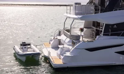 Mary's Grace: Bote auxiliar inflável amarrado aos degraus da popa de um catamarã em águas ensolaradas