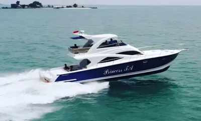 Princess TA: Yate a motor de casco azul oscuro a gran velocidad sobre un mar turquesa cerca de una isla pequeña