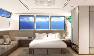 Velocean: Renderização de uma cabine com cama de casal sob três janelas, sofá e guarda-roupa
