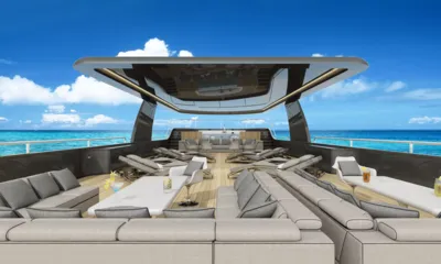 Velocean: Renderização de um deck superior com sofás lounge cinza, espreguiçadeiras e um hardtop sob o céu azul