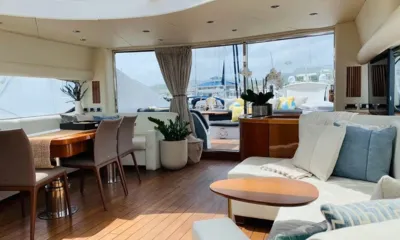 Hecht Yeah: Salão claro com sofás brancos, piso de madeira, mesa de jantar e grandes janelas para o deck de popa