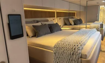My Maria: Cabine com cama de casal, almofadas cinza, manta de tricô grossa, parede espelhada e tablet na parede