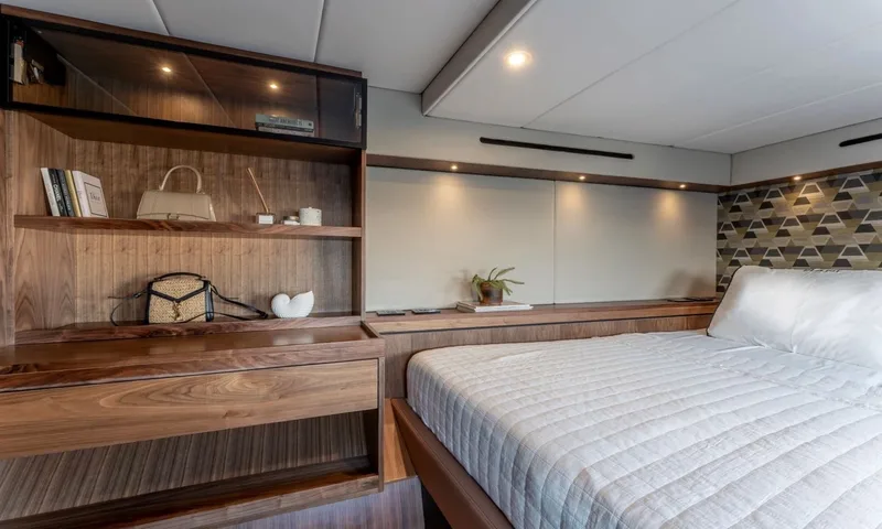 Hani I: Cabin with white quilted bed, wooden shelving and patterned headboard wall