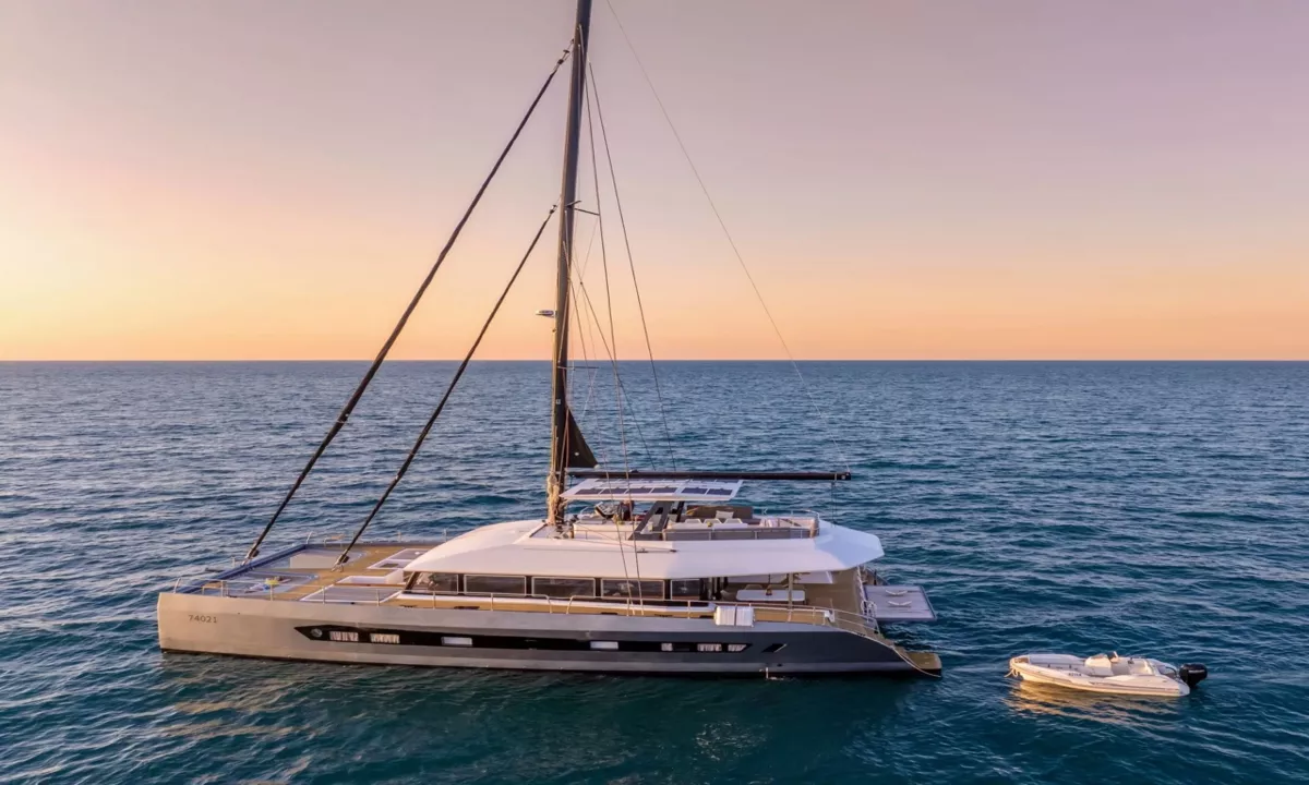Hani I: Sailing catamaran on open sea at sunset, seen from slightly above with mast and solar panels