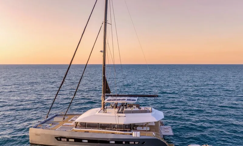 Hani I: Sailing catamaran on open sea at sunset, seen from slightly above with mast and solar panels