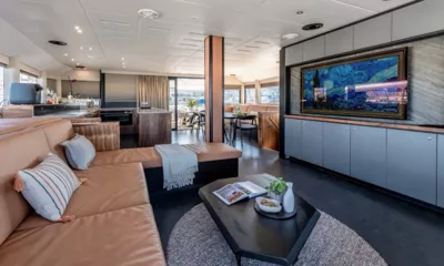 Hani I: Saloon with tan leather sofa, dark coffee table, framed artwork screen and dining area beyond