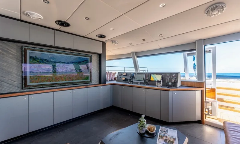 Hani I: Saloon with framed artwork screen, grey cabinets and helm console by forward windows