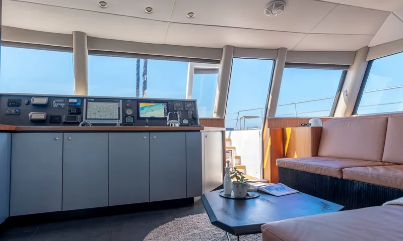 Hani I: Interior helm station with navigation screens beside lounge sofa and coffee table