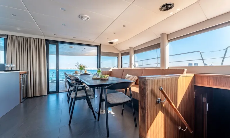 Hani I: Indoor dining table with chairs and bench seating beside large sea view windows
