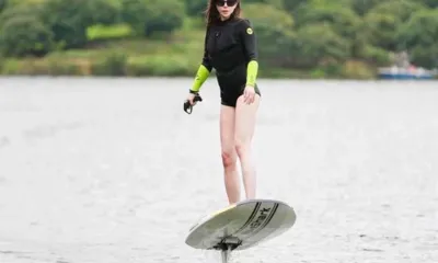 WaveShark II: Mulher de roupa de neoprene andando em uma prancha de surfe elétrica com hidrofólio sobre águas calmas