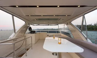 Legend S: Flybridge coberto com mesa branca, assentos em volta e bancada de churrasqueira com vista para o mar