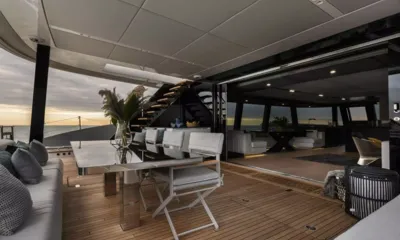 XMotion: Deck de popa coberto com mesa de jantar, cadeiras e escada, aberto para o salão