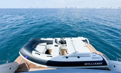 Spysea: Bote auxiliar inflável sobre a plataforma de popa de teca, com mar aberto e o horizonte da cidade ao fundo