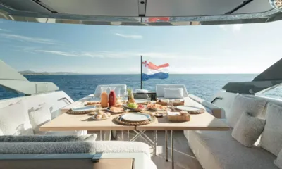 Bluegame74: Outdoor table set with breakfast, juices and fruit, overlooking the sea and a flag