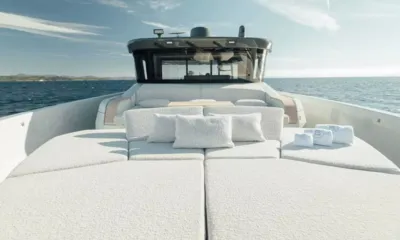 Bluegame74: Large foredeck sunpad with cushions and rolled towels in front of the wheelhouse windows