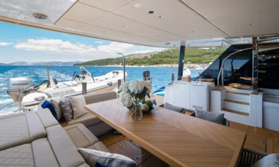 Dessus: Table à manger ombragée sur le pont arrière avec fleurs, sièges lounge et une annexe en remorque derrière